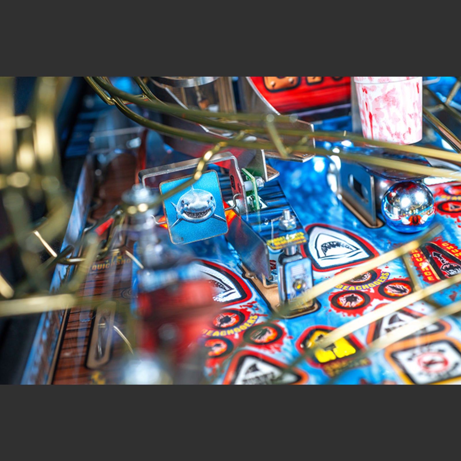 Nitro Pinball Sales Jaws 50th Annyversary Close-up of a pinball machine with colorful design and various components.