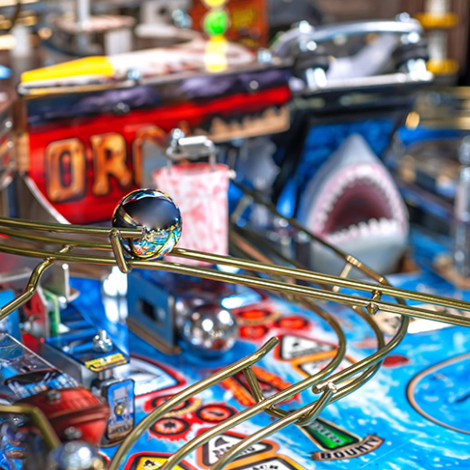 Nitro Pinball Sales Jaws 50th Annyversary Close-up of a pinball machine with a shark figure and colorful playfield.