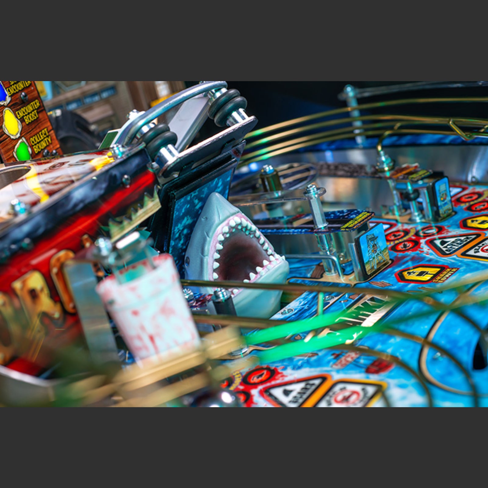 Nitro Pinball Sales Jaws 50th Annyversary Close-up of a pinball machine with a shark figure and colorful design.