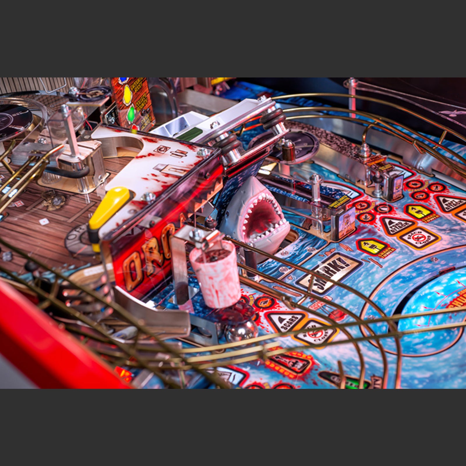 Nitro Pinball Sales Jaws 50th Annyversary Close-up of a pinball machine with a shark figure and colorful design.